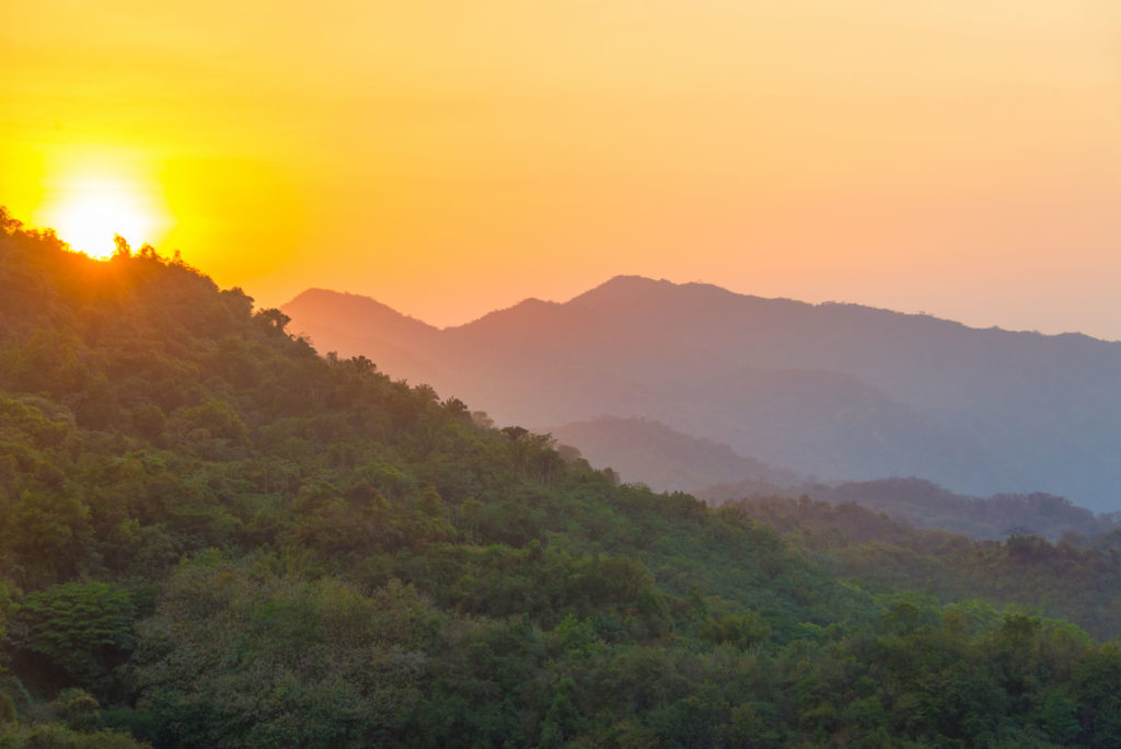 Sun setting over lush green hills in the Sierra Nevada de Santa Marta mountain range in Colombia. Photograph by: Jesse Kraft